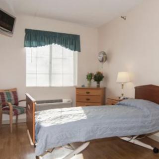 A minimalist bedroom with a single bed, dresser, and window with curtains.