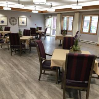 A well-lit dining area featuring tables and chairs arranged for a communal dining experience.
