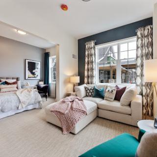 A stylish and inviting multifunctional space featuring a comfortable couch, decorative pillows, and ample natural light.