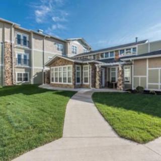 A residential building with a well-maintained lawn and a clear sky.