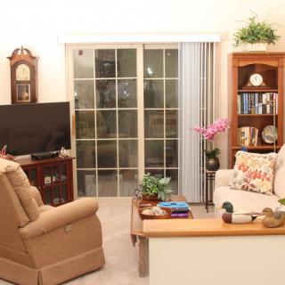 A cozy living room with a comfortable armchair, television, bookshelf, and sliding glass doors.