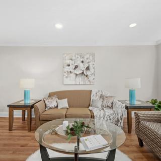 A cozy living room featuring a comfortable sofa, glass coffee table, and modern decor.