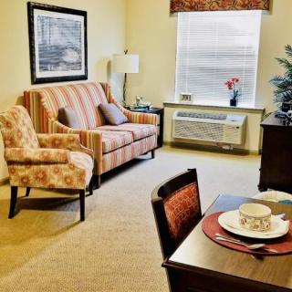 A cozy living room with a sofa, armchair, and dining table set near a window.