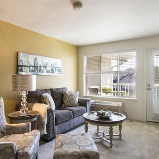 A cozy living room with a sofa, armchairs, and a coffee table near a window that lets in natural light.
