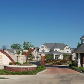 Entrance to a gated residential community with landscaped driveways and large houses.