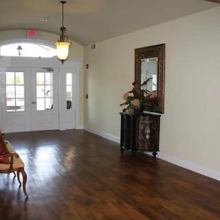 A spacious entrance hallway with wooden floors, a decorative table, and a mirror.