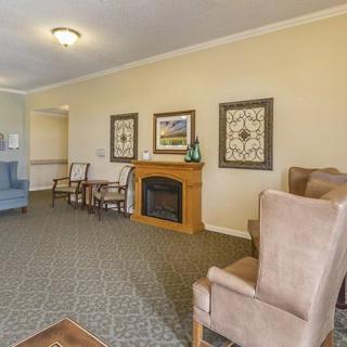 A cozy living room with armchairs, a fireplace, and decorative wall art.