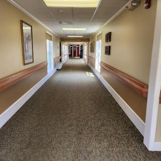 A well-lit and spacious hallway featuring decorative wall art and a carpeted floor.