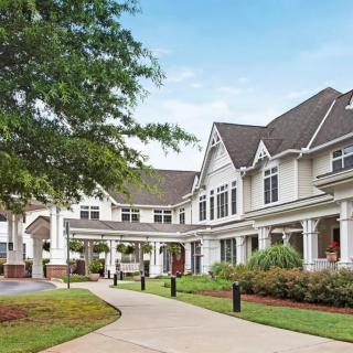 A charming residential building with a well-maintained pathway and lush landscaping.