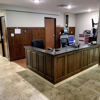 A modern office reception area with a wooden front desk and workspace.