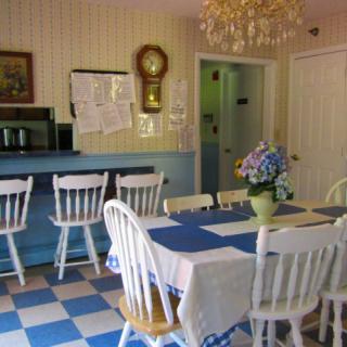 A cozy kitchen with a dining table and chairs, featuring blue and white decor and a checkered floor.