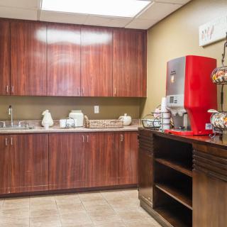 A small kitchen area with a coffee station and wooden cabinets.