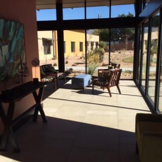A modern sunroom with large glass windows, furniture, and a view of the outdoors.