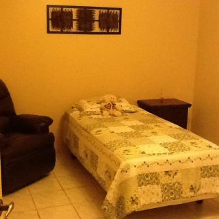 A simple bedroom with a single bed, a recliner chair, and a nightstand.