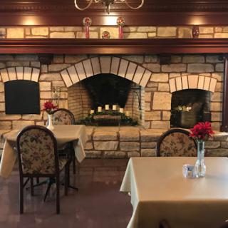 An inviting restaurant interior featuring charming tables and a cozy fireplace.