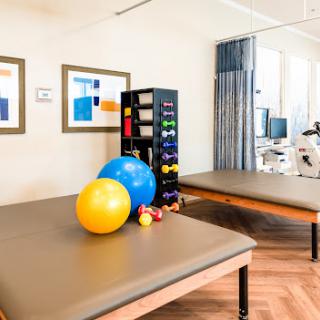 A well-equipped therapy room featuring exercise balls, weights, and comfortable treatment surfaces.