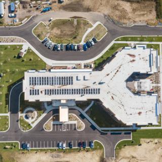 An aerial view of a modern building surrounded by organized parking areas and landscaped grounds.