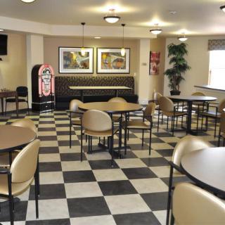 An empty cafe with checkered flooring, round tables, and a jukebox.
