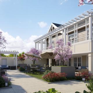 A beautiful outdoor patio area with seating, surrounded by well-maintained gardens and a modern building.