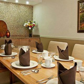 A neatly set dining table with folded napkins and floral centerpiece in a cozy dining room.
