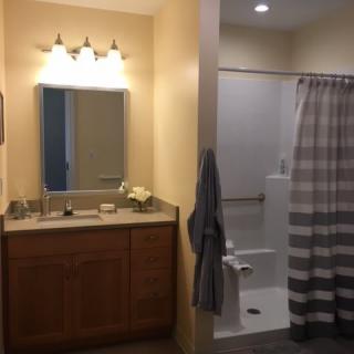 A bathroom with a mirror and vanity on the left, and a shower with a striped curtain on the right.