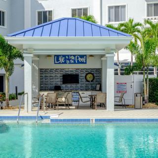 An inviting outdoor pool with a bar and seating area, surrounded by palm trees at a hotel.