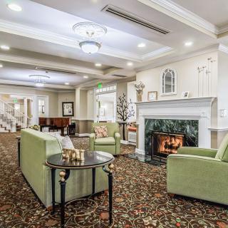 A cozy living room with a fireplace, green armchairs, and elegant decor.