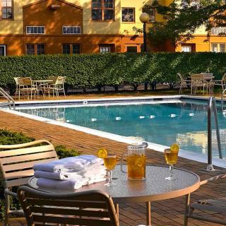 Outdoor swimming pool area with tables and chairs, featuring refreshments and towels for relaxation.