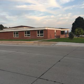 A brick school building set against a cloudy sky.