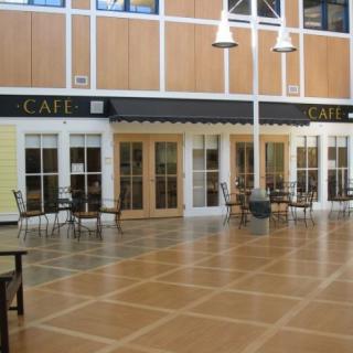 An empty cafe interior featuring wooden floors and neatly arranged tables and chairs.