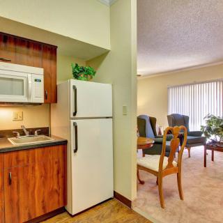A compact kitchen area with a refrigerator and microwave, adjacent to a cozy living room with seating and natural light.