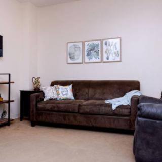 A cozy living room featuring a brown sofa, decorative cushions, and wall art.
