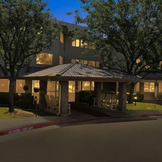 A well-lit building entrance at night with surrounding trees.