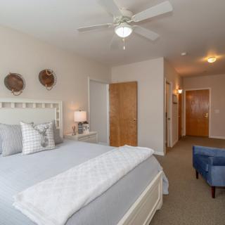 A cozy and minimalist bedroom with a large bed, ceiling fan, and soft lighting.
