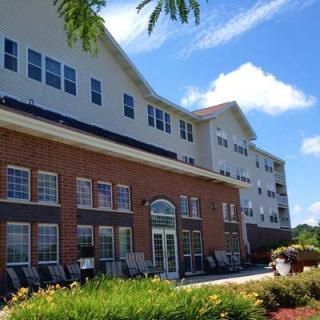 A sunny day view of a residential apartment building with well-maintained landscaping.