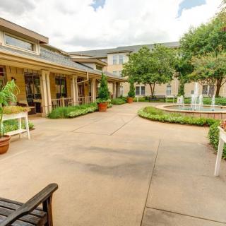 A tranquil courtyard with a central fountain, surrounded by lush greenery and outdoor seating areas.