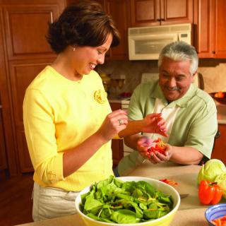 A man and a woman preparing a salad together in the kitchen.