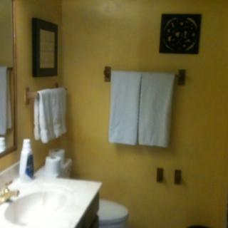 A bathroom with towels hanging on the wall and a sink with toiletries.