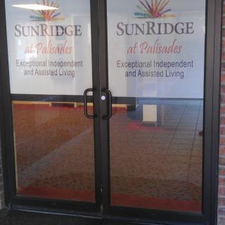 Entrance to SunRidge at Palisades, featuring glass doors with signage for independent and assisted living.