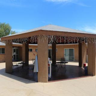 A large outdoor gazebo with furniture set up underneath on a sunny day.