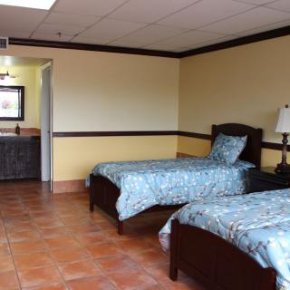 A hotel room with two single beds and tile flooring.