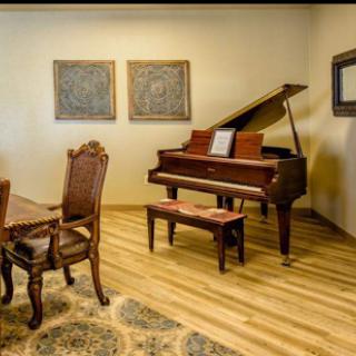 A cozy interior featuring a grand piano and elegant wooden dining set, complemented by decorative art pieces on the wall.