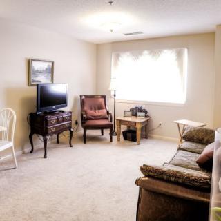 A cozy living room with a television, chairs, and a sofa.