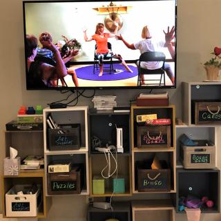 A living room setup with a TV mounted on the wall above organized storage shelves.