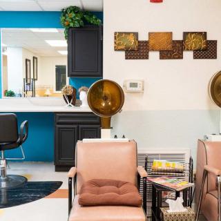 A cozy salon interior featuring comfortable seating, hair dryers, and stylish decor.