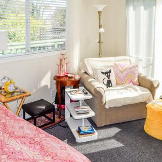 A cozy living room corner with a comfortable chair, side tables, and a standing lamp.