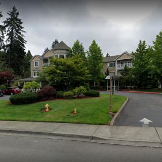 A large house surrounded by trees and a well-maintained garden on an overcast day.