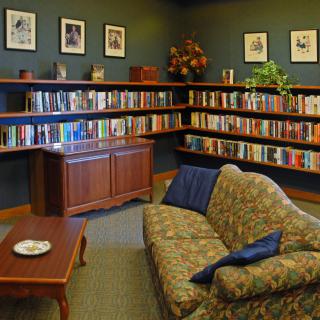 A cozy library with bookshelves, a sofa, and a coffee table.