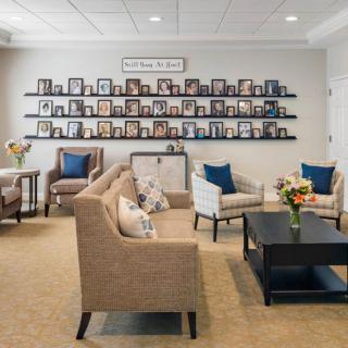 A cozy office lobby with comfortable seating and walls adorned with photo frames.