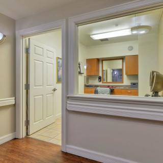 A view of a professional office hallway with a reception window and doorway.